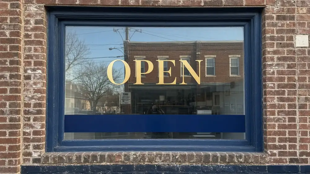 Gold 'Open' lettering and navy business-name band on a storefront window